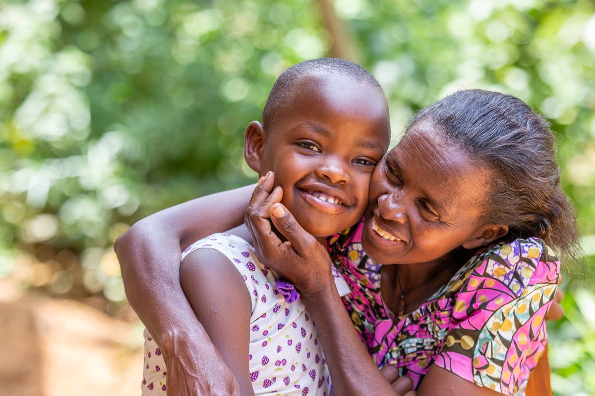 Happy Rwandan mother and daughter together in front of their home