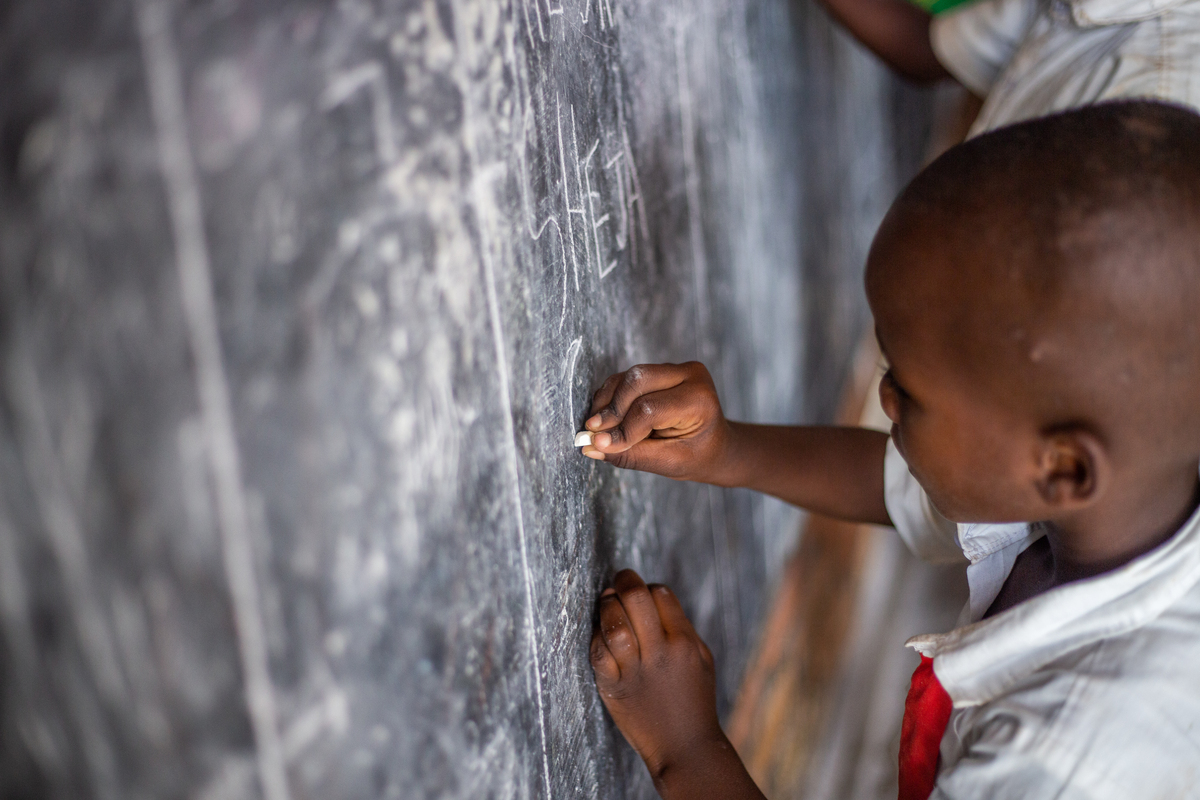 An African schoolchild draws on a blackboard with chalk