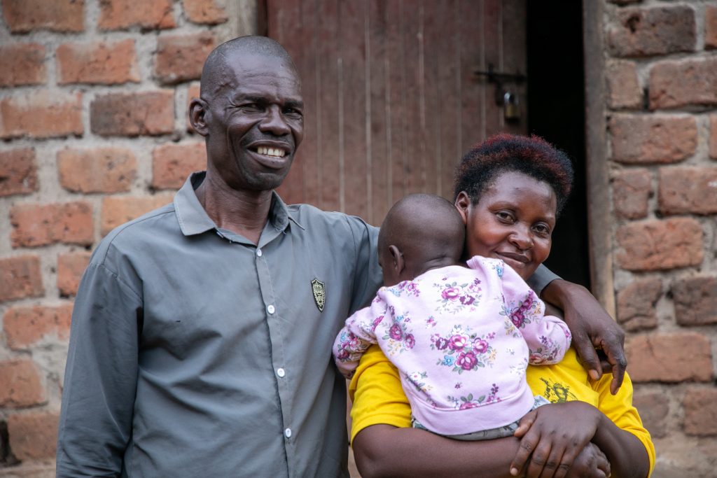 Happy ugandan family hugging outside their house
